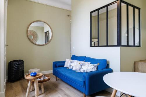 un salon avec un canapé bleu et un miroir dans l'établissement Lueur Provençale, à Villeneuve-Loubet