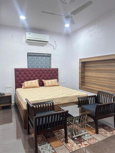 a bedroom with a large bed and two chairs at Phulkari Hospitality Dhanbad in Dhanbād