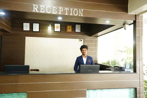 a man standing at a reception desk with a laptop at Hotel Grand Bee , Yeshwanthpur Junction in Bengaluru