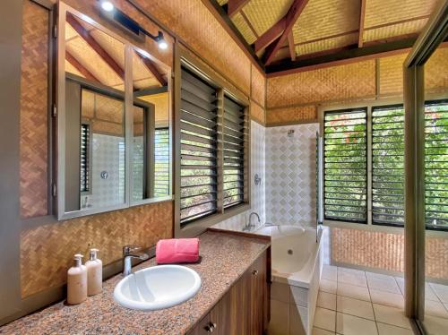a bathroom with a sink and a tub and a mirror at Absolute Beachfront and Pool House in Horseshoe Bay
