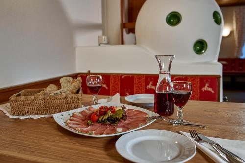 a table with a plate of food and two glasses of wine at Hotel Jägerhof in Oetz