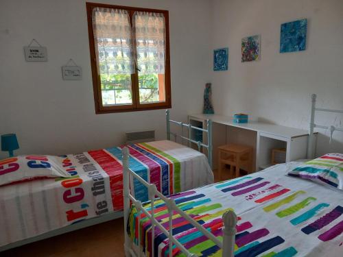 une chambre avec deux lits et un bureau et une fenêtre dans l'établissement Gite à la campagne ST BLAISE 06670, à Saint-Blaise