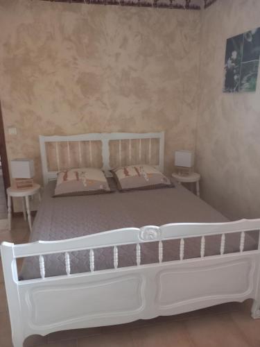 - un lit blanc dans une chambre avec 2 tables dans l'établissement Gite à la campagne ST BLAISE 06670, à Saint-Blaise