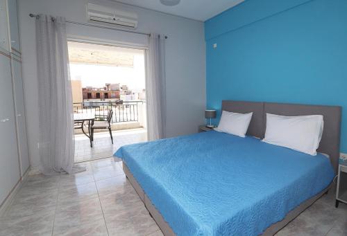 Dormitorio azul con cama y ventana grande en Casa alle terme, en Loutra Edipsou