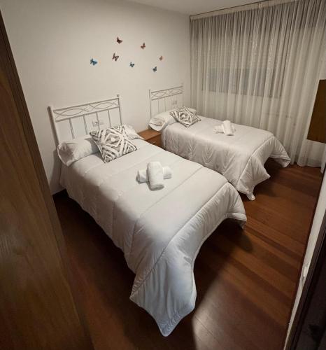 two beds with white sheets in a room at Apartamento Barbanza Arousa in Boiro
