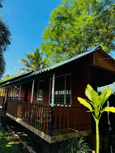 a red house with a wooden fence in front of it at Ro Villa in Weligama