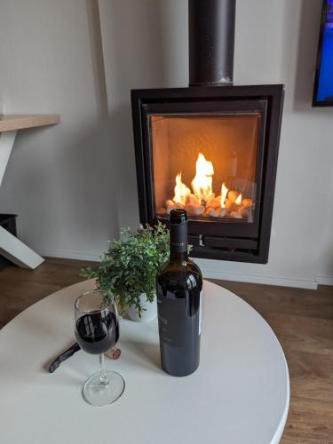 a bottle of wine and a glass on a table with a fireplace at huisje aan zee in Hellevoetsluis
