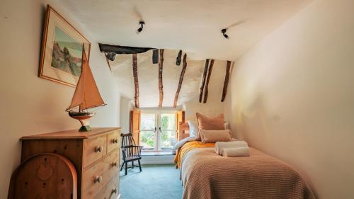 une chambre avec deux lits et une commode et une fenêtre dans l'établissement Stunning 4-Bed Thatched Cottage in Oxfordshire!, à Ledwell