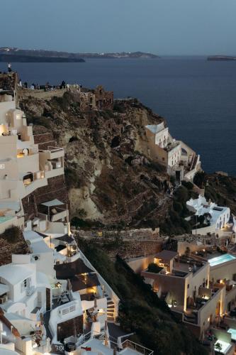 a group of white buildings on a hill with the ocean at Nano Oia Villas in Oia