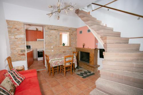 a living room with a staircase and a table and a fireplace at Nefeli House Agios Georgios Sykousis Chios in Chios