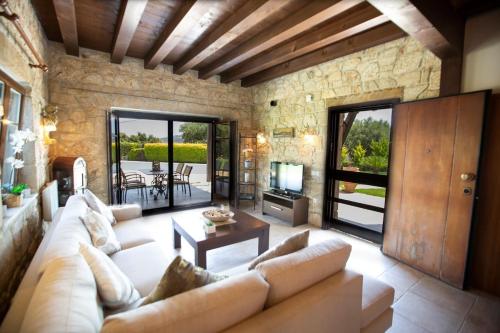 a living room with a couch and a tv and a table at Eco Stone Villa with Private Pool and Jacuzzi in Kalandra