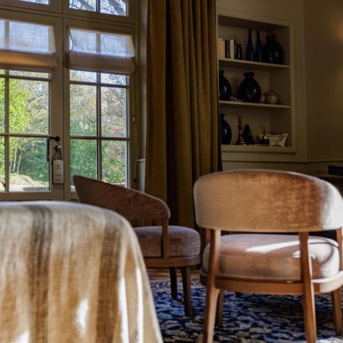 a room with two chairs and a table and a window at Domaine de Locguénolé & Spa - Relais & Chateaux in Kervignac