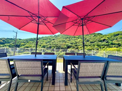 two tables with red umbrellas on a patio at Sunset Villa Shirahama 5 min to the beach Pets OK in Shimoda