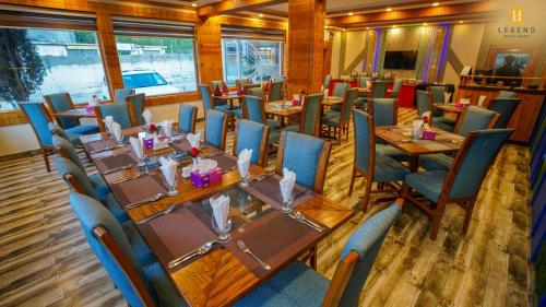 a dining room with wooden tables and blue chairs at Legend Hotel Skardu in Skardu