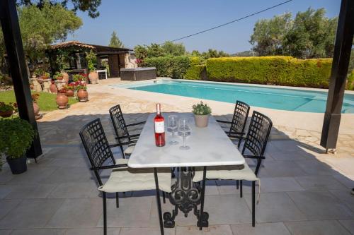 a table with a bottle of wine on it next to a pool at Eco Stone Villa with Private Pool and Jacuzzi in Kalandra