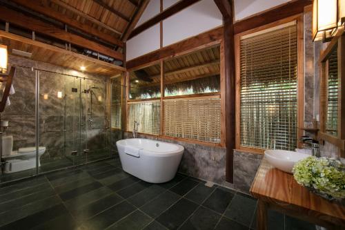 a bathroom with two sinks and a tub and a shower at Mai Chau Hideaway Lake Resort in Mai Chau