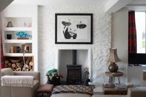 a living room with a cow picture on the wall at Large Open Plan Cottage with Balcony BBQ Area in Calstock