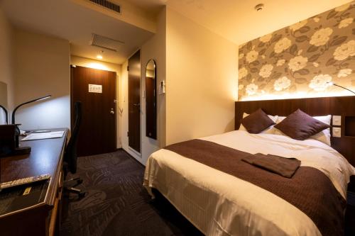a hotel room with a large bed and a dresser at Kushiro Century Castle Hotel in Kushiro