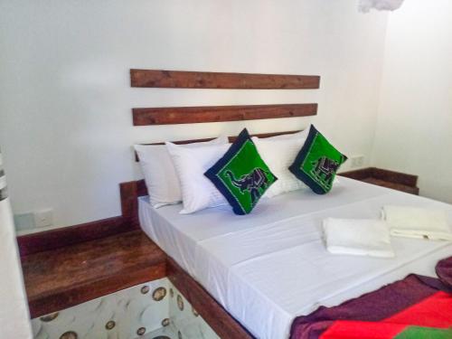 a bedroom with a white bed with green and white pillows at Sigiriya Moon Mirage Villa in Sigiriya