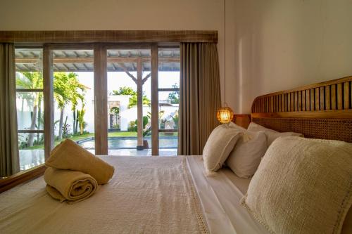 a bedroom with a large bed with a large window at Simple & Magical Villas PRAYA in Seminyak