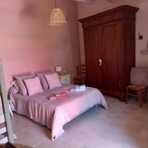 une chambre avec un lit avec des oreillers roses dans l'établissement Boufavent, à Salettes