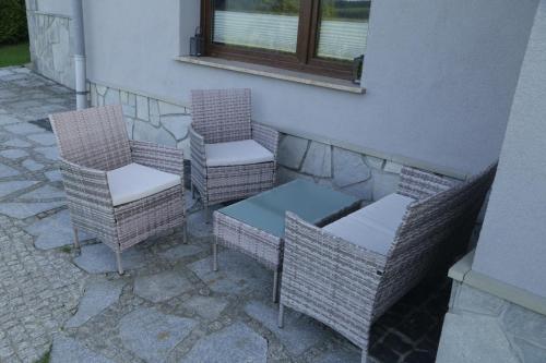 three wicker chairs and a table and a window at Apartament w ogrodzie in Tylka