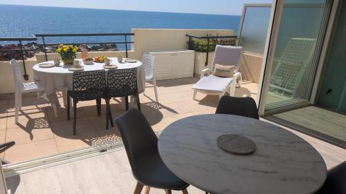 un balcon avec une table et des chaises et l'océan dans l'établissement T3 refait à neuf vue mer, piscine, clim, garage, wifi, à Sète