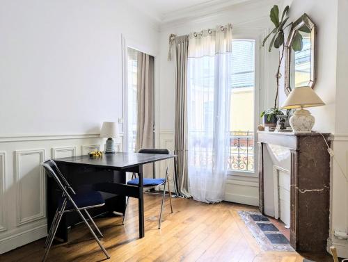 une table et des chaises dans une pièce avec une fenêtre dans l'établissement Charming light flat in Goncourt, à Paris