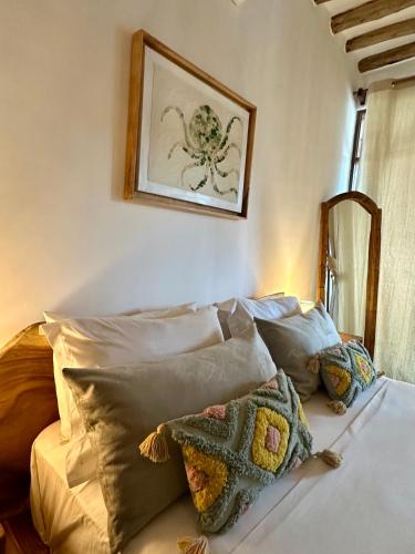 a bed with a bunch of pillows on it at Olamanga Beach Villa Adults Only in Jambiani