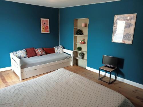 Cette chambre bleue dispose d'un canapé et d'une télévision. dans l'établissement Close to Beaches and Bayeux, à Tour-en-Bessin