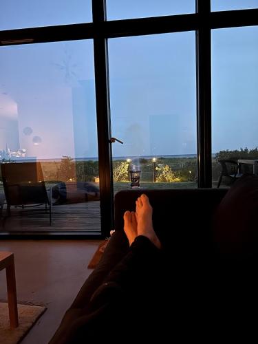 a person sitting on a couch looking out a window at Bright and modern villa by the sea in Trelleborg