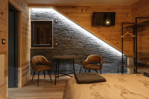 a bedroom with a bed and chairs and a brick wall at Apart Hôtel des Cols in Bordères-Louron