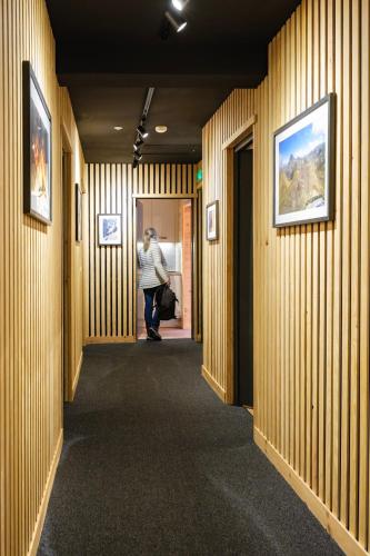 a person walking down a hallway with wood paneled walls at Apart Hôtel des Cols in Bordères-Louron