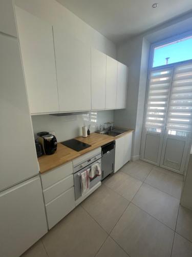 une cuisine avec des armoires blanches, un évier et une cuisinière dans l'établissement Cosy apartment, à Cannes