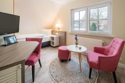 a room with two chairs and a table and a bed at Hotel Inselfriede in Spiekeroog