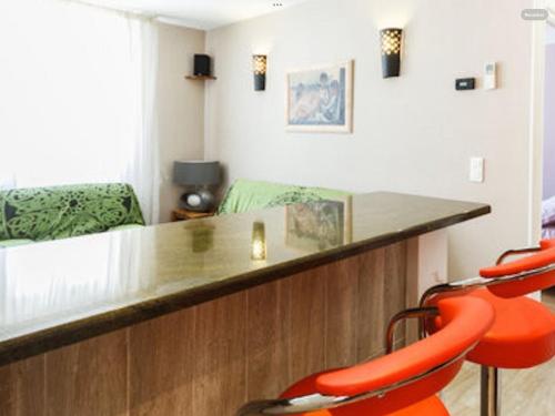 une pièce avec un bar avec des chaises orange et un canapé dans l'établissement My appartement Perpignan 50m2, à Perpignan