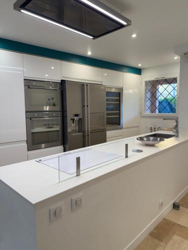 une grande cuisine blanche avec des appareils électroménagers en acier inoxydable dans l'établissement Maison avec jacuzzi privatif dans résidence, à La Gaude