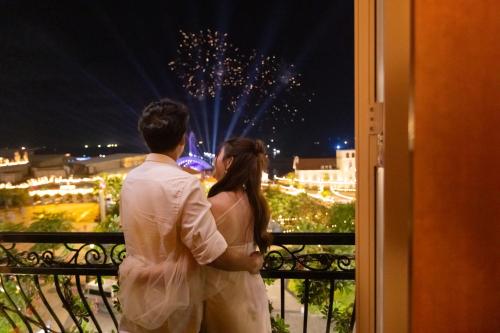 a man and woman standing on a balcony looking at fireworks at Sakurakyo Hotel & Spa Phu Quoc - Free Hon Thom Island Waterpark Cable Car Until 15 December 2025 in Phu Quoc