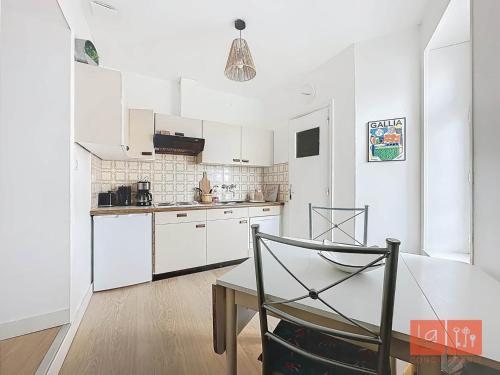 une cuisine avec des armoires blanches et une table à l'intérieur dans l'établissement Studio du Cairn, à Wimereux