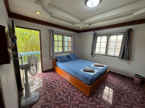 a bedroom with a blue bed and a window at Tommy apartment in Koh Tao