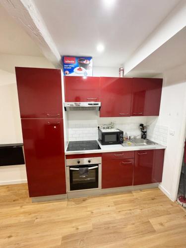 La cuisine est équipée de placards rouges et d'un four avec plaques de cuisson. dans l'établissement Appartement proche du centre ville, à Marseille