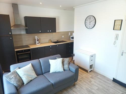 un salon avec un canapé bleu et une cuisine dans l'établissement Appartement T2 N3, Proche Naval Group et Centre Ville, à Cherbourg en Cotentin