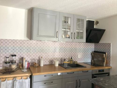 une cuisine avec des armoires blanches et un évier dans l'établissement Logement 4 pers - Béziers au bord du Canal du Midi à prox des plages, à Béziers