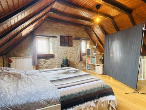 une chambre avec un grand lit et un mur en pierre dans l'établissement La HULOTTE, à Balsac