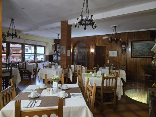 a dining room with white tables and wooden walls at Hosteria Picos De Europa in Potes