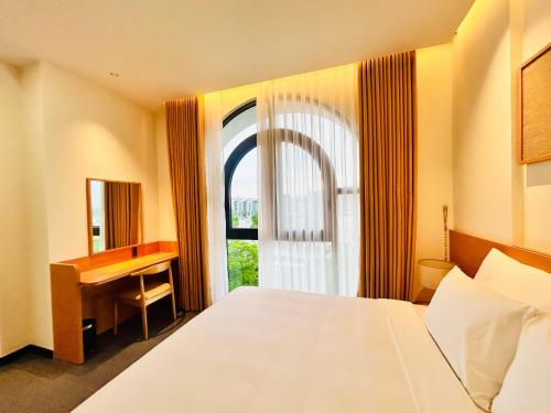 a bedroom with a bed and a desk and a window at Thai Hoang Villa Quảng Bình in Dong Hoi