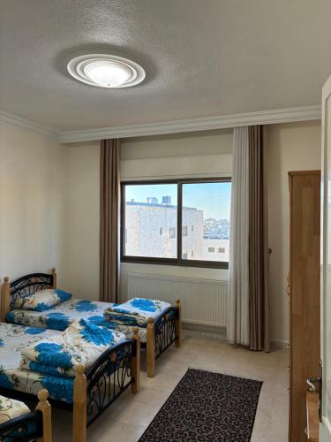 a bedroom with two beds and a window at Furnished Family Apartment in Dahyet Al-Rasheed in Amman