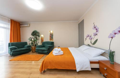 a bedroom with a bed and two green chairs at Apartment on Maidan, Khreschatyk 4 street in Kyiv