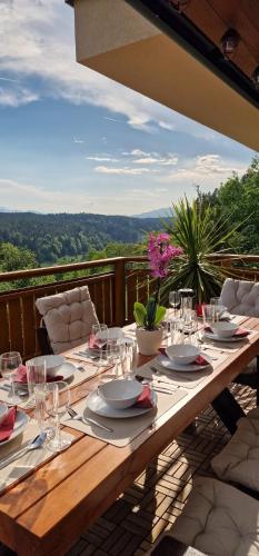 a wooden table with plates and glasses on a balcony at Villa Sara - Wörtherseeblick, Sauna, Panoramaterrasse in Sankt Bartlmä