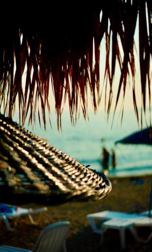 a straw umbrella and chairs on a beach at Club Afrodit Tatil Köyü in Altınoluk